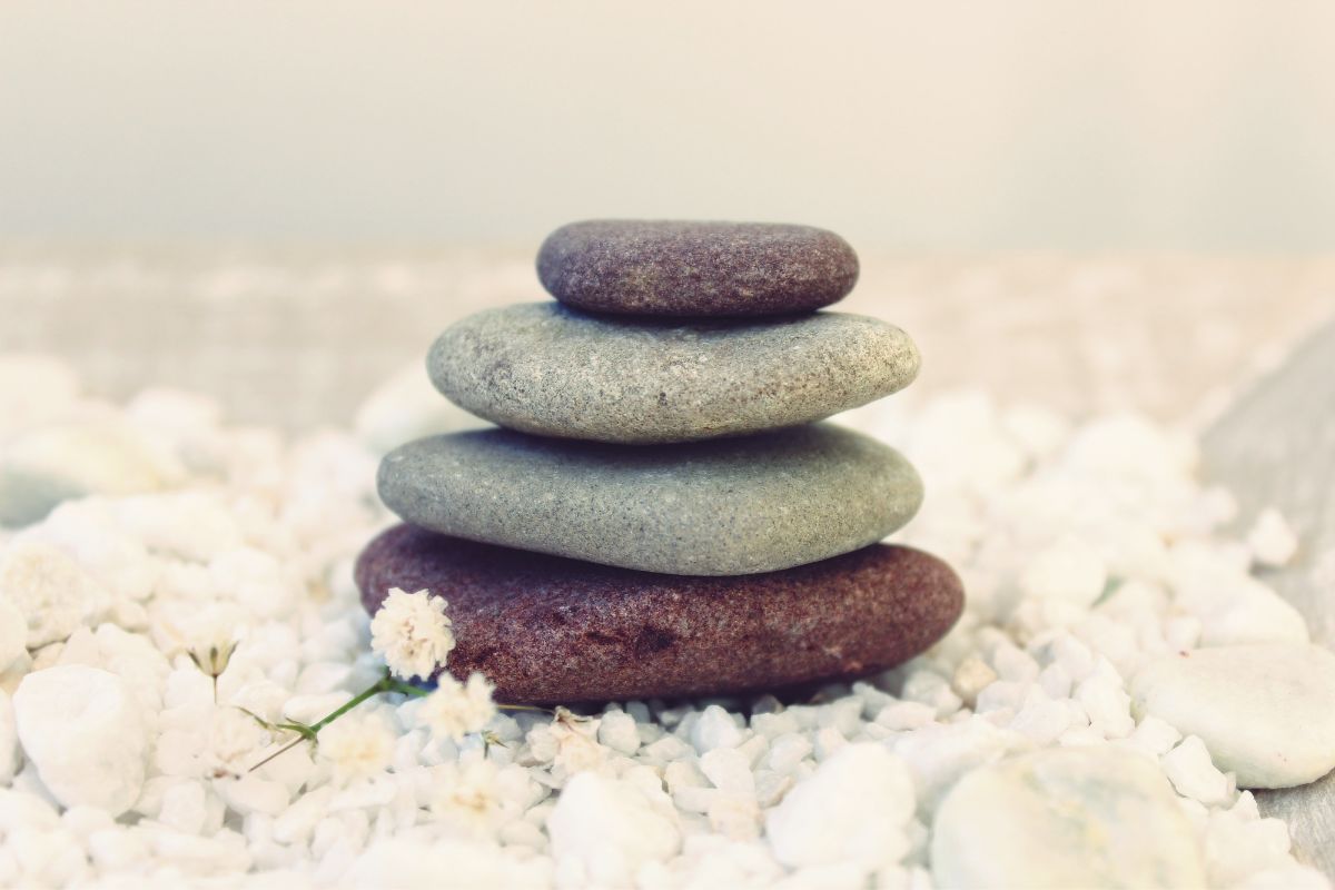 Image of four smooth, rounded rocks on a surface, representing the calming and grounding benefits of using Nozey's Active Strips for mindfulness and meditation. The rocks serve as a visual metaphor for the sense of peace and stability that can be achieved through the use of Active Strips, which provide support and reduce congestion during physical activities.